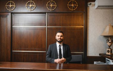 Otel lobisinde çalışan profesyonel bir resepsiyonist misafirlere konukseverlik ve hizmet sunuyor.