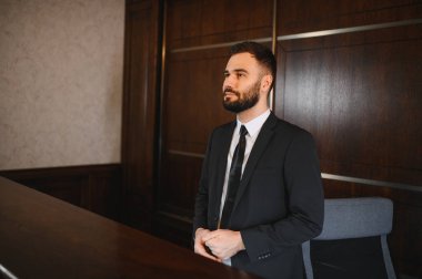 Takım elbiseli bir adam otel ya da iş resepsiyonisti olarak çalışıyor, konukseverlik ve şirket müşterileri için profesyonel hizmet sunuyor.