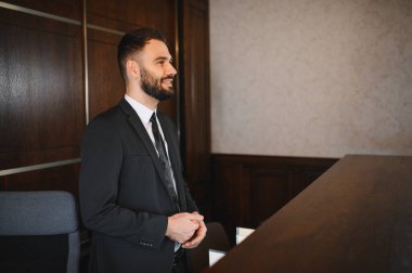 Takım elbiseli genç işadamı, otel ya da etkinlik resepsiyonisti olarak çalışıyor, profesyonel bir çevrede mükemmel hizmet veriyor.