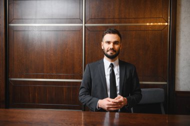 Takım elbiseli ve kravatlı profesyonel bir adam. Otel resepsiyonunda ya da resepsiyonda çalışıyor. Hizmet veriyor.