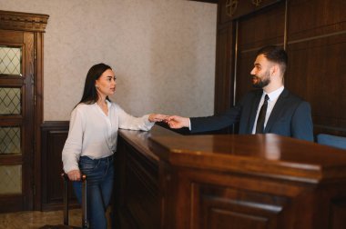 Misafir otel resepsiyonuna giriş yapıyor, resepsiyonist yakınlarda valizli anahtar kartı teslim ediyor, profesyonel karşılama ve servis.