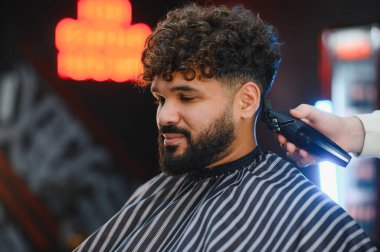 Müşterinin yeni bir saç stili ve berberin soluk saçı var. Taze bir görünüm için saç makası kullanıyor.