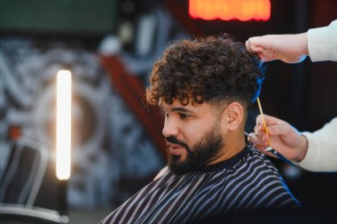 Bir berberden şık bir saç kesimi alan müşteri, profesyonel bir kuaförde kuaförlük ve modern kuaförlüğe odaklanmış.