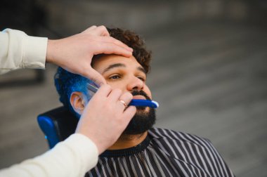 Berber bir adamın favorilerini ustura ile dikkatlice şekillendirir ve traş eder. Profesyonel bakım hizmeti sunar.