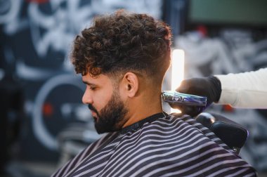 Profesyonel berber, bir berber dükkanında erkek müşterisinin soluk saç kesimini kesiyor. Saç bakımına ve modern stile odaklanıyorum.