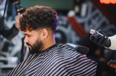 Profesyonel saç kesimi hizmeti veren müşteri modern bir berber dükkanında şık bir solgunluk ve sakal kesimi alıyor.