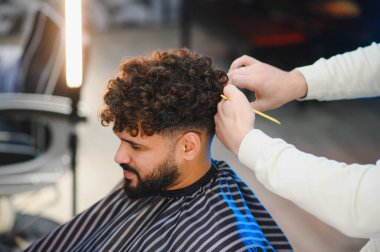 Modern berber dükkanında saç ve makaslarla profesyonel saç kesim hizmeti alan bir adam. Saç stilisti, erkeklerin bakımında çalışıyor.