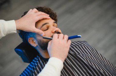 Profesyonel berber stili ve bir adamın sakalını keskin bir ustura ile kesme yüz bakımı ve kişisel bakım için.