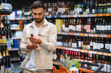 Alkol reyonunda şarap şişesini inceleyen bir adam alışveriş arabasıyla alışveriş yapmaya karar veriyor.