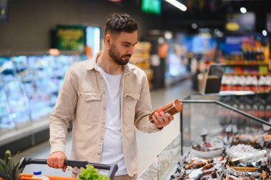 Markette alışveriş arabasını iten bir adam yiyecek seçimini yapıyor.