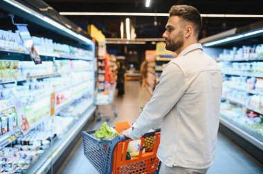 Müşteri, günlük gıda alışverişi, tüketici yaşam tarzı konsepti sırasında parlak bir perakende mağazası koridorunda ürünleri seçiyor