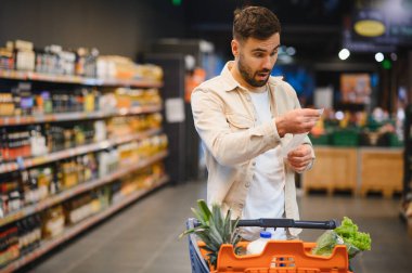 Adam süpermarket faturasına şaşırmış görünüyor, harcamaları hesaplıyor ve yiyecek alırken enflasyonla karşı karşıya kalıyor