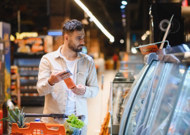Bir adam marketten taze balık seçiyor, sağlıklı yiyecek alışverişi yapıyor ve bilinçli beslenme tercihleri yapıyor.