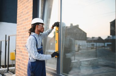 Profesyonel inşaat işçisi, tuğla bir binaya yeni bir pencere çerçevesi yerleştiriyor.