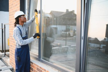 İnşaat işçisi pencere çerçevesini ruh seviyesiyle kontrol ederek modern ev inşaatı projesinde eksiksiz kurulum sağlamış.