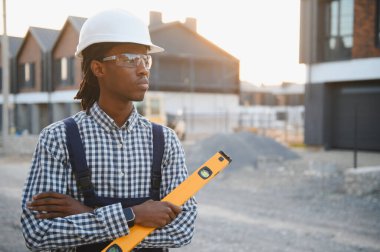 Siyahi inşaat işçisi bir inşaat sahasında ruhsal bir seviyede tutarak ilerleme kaydediyor ve gelecekteki konut gelişimini planlıyor.