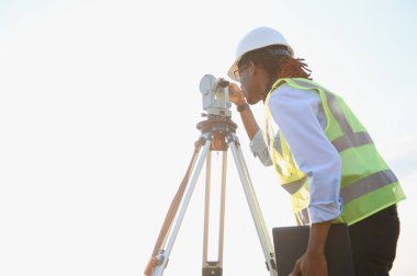 Arazi ölçümü ve haritalama için toplam istasyon enstrümanı kullanan bir inşaat projesinde çalışan kadın araştırmacı