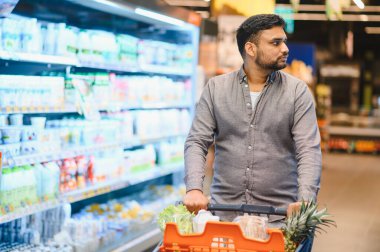 İnsan market alışverişi yaparken raflardan ürün seçiyor, tüketici yaşam tarzını ve modern perakende deneyimini vurguluyor
