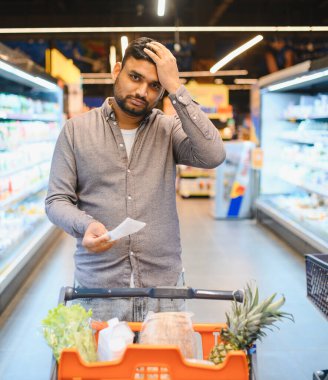 Adam elinde bir süpermarket makbuzu tutarken endişeli görünüyor, mali gerilim, tüketici fiyat artışı ve enflasyon yaşıyor