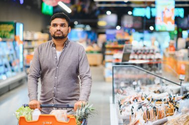 Marketi market poşetleriyle dolduran adam. Tüketici gıda ürünleri alıyor, bakkaldan ürünler seçiyor