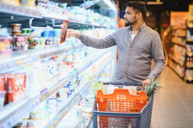 Market alışverişi, modern bir perakende mağazasındaki soğutuculu raftan ürün seçmek, bir alışveriş arabasını itmek...