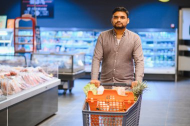 Market koridorunda alışveriş yapan, alışveriş yapan bir adam. Tüketim, perakende ve günlük yaşam konsepti