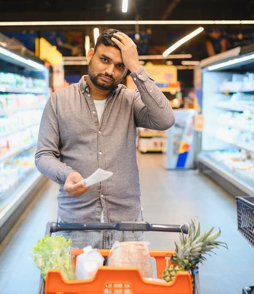 Adam elinde bir süpermarket makbuzu tutarken endişeli görünüyor, mali gerilim, tüketici fiyat artışı ve enflasyon yaşıyor