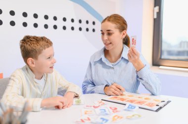 Konuşma terapisti, renkli bilgi kartları kullanarak, çocuk gelişimi ve erken eğitime odaklanarak, bir çocuğun mektupları öğrenmesine yardım ediyor.