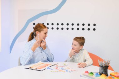 Konuşma terapisti bir çocukla seans sırasında, dil gelişimi için bir araç ve mektup kartı kullanarak konuşmada yardımcı oluyor.