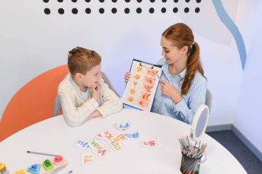 Konuşma terapisti, konuşma ve konuşma gelişimine odaklanan, bir ders sırasında küçük bir çocuğa konuşma egzersizleri anlatıyor.