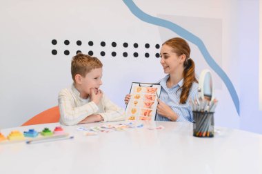 Konuşma terapisti genç bir çocukla çalışıyor, öğrenim sırasında iletişim ve duygusal ifade konusunda yardımcı oluyor.