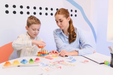 Bayan bir öğretmenle oyun oynayan genç bir çocuk eğitim ortamında bilişsel ve motor becerilerini geliştiriyor.