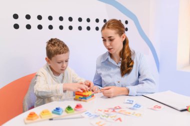 Terapist, çocuğa bilişsel gelişim için eğitici oyuncaklar ve parlak bir odada erken öğrenme konusunda yardım ediyor.