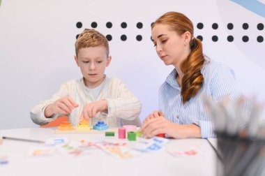 Renkli ahşap oyuncaklarla oynayan liseli çocuk, kadın bir öğretmenle iyi motor becerileri geliştiriyor.