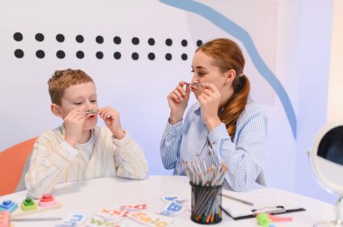 Çocuk ve terapist konuşma, iletişim ve öğrenme becerilerini geliştirmek için araçlarla oral motor egzersizleri yapıyorlar.