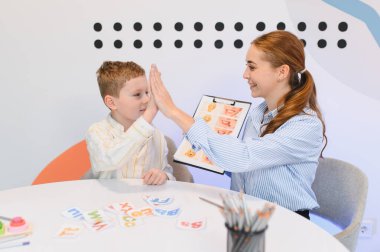 Genç müşteri terapi seansı sırasında konuşma dili patologuna beşlik çakıyor, gelişimi ve gelişimi kutluyor.