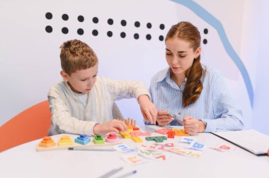 Çocuk terapist veya öğretmenle eğitim faaliyetleri yapıyor, beceri geliştirme ve erken eğitim üzerine çalışıyor