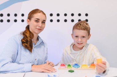 Öğretmen ve çocuk birlikte çalışıyor, modern eğitim ortamında renkli tasnif blokları ile iyi motor ve bilişsel beceriler geliştiriyor.