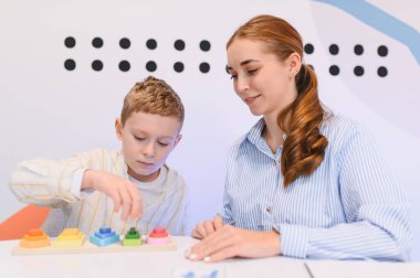 Çocuk renkli bir oyuncağı oynarken terapisti ya da öğretmeni bilişsel gelişime ve çocukluk eğitimine yardım ediyor.