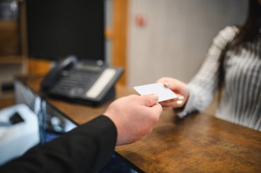 Müşteri otele giriş yapıyor, kasanın arkasındaki kadın resepsiyonistten boş bir anahtar ya da kredi kartı alıyor.