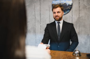 Profesyonel otel resepsiyonisti. Bağlantı kurulamayan kart ödemeleri için terminali sunuyor. Müşteri hizmetleri sunuyor.
