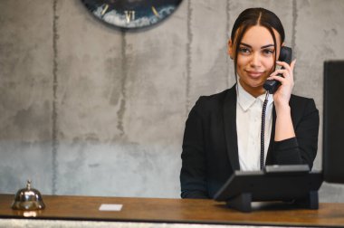 Gülümseyen kadın otel resepsiyonunda ya da ofiste mükemmel müşteri hizmeti ve konukseverlik sunuyor.