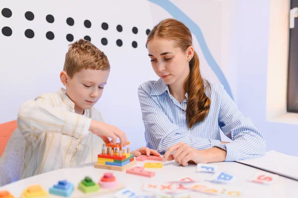 Genç bir çocuk, bir bayan öğretmenle oyun oynuyor. Öğrenme, konsantrasyon ve motor becerilere odaklanıyor.