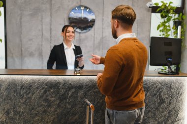 Otel resepsiyonunda kontrol için kadın kapıcıya pasaport veren konuk, konukseverlik hizmeti sunuyor.