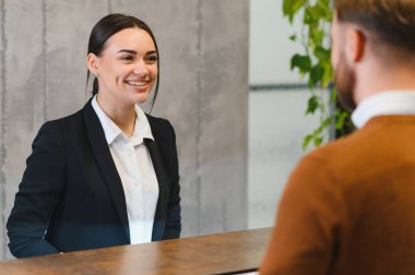 Dost canlısı kadın müşteri hizmetlerinde çalışıyor, otel misafirini karşılıyor. Mükemmel bir konukseverlik ve yardım sağlıyorlar.