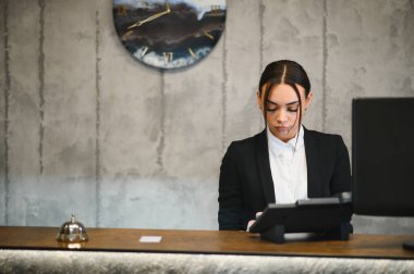 Kadın otel kapıcısı tezgahtaki işe odaklanarak profesyonel bir ortamda konukseverlik hizmeti veriyor.