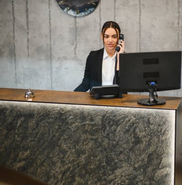 Otel ya da ofis lobisinde çalışan arkadaş canlısı bir resepsiyonist, misafir servisi ve konukseverlik desteği için çağrıda bulunuyor.