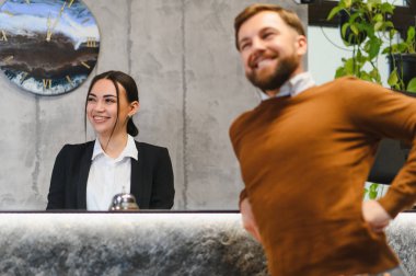 Arkadaş canlısı resepsiyonist müşteri hizmetleri sunuyor. Modern otel resepsiyonunda sırt ağrısı çeken bir misafiri kontrol ediyor.