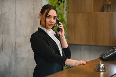 Profesyonel otel resepsiyonisti ya da kapıcısı olarak çalışan genç bir kadın, müşteri hizmetleri sunuyor ve aramaları yönetiyor