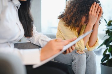 Hintli psikolog, genç bir kadına yardım ediyor. Yüzünü kapatıyor. Stres ve zihinsel sağlık sorunları yaşıyor.